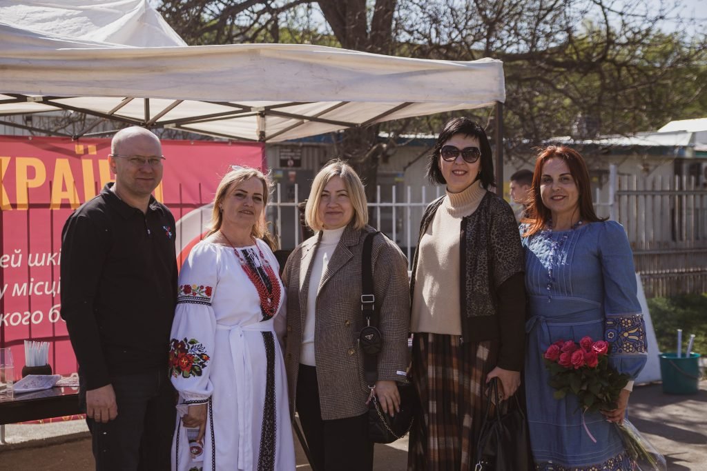 Учителі ліцею та садочка «Мої обрії» біля прапора України.